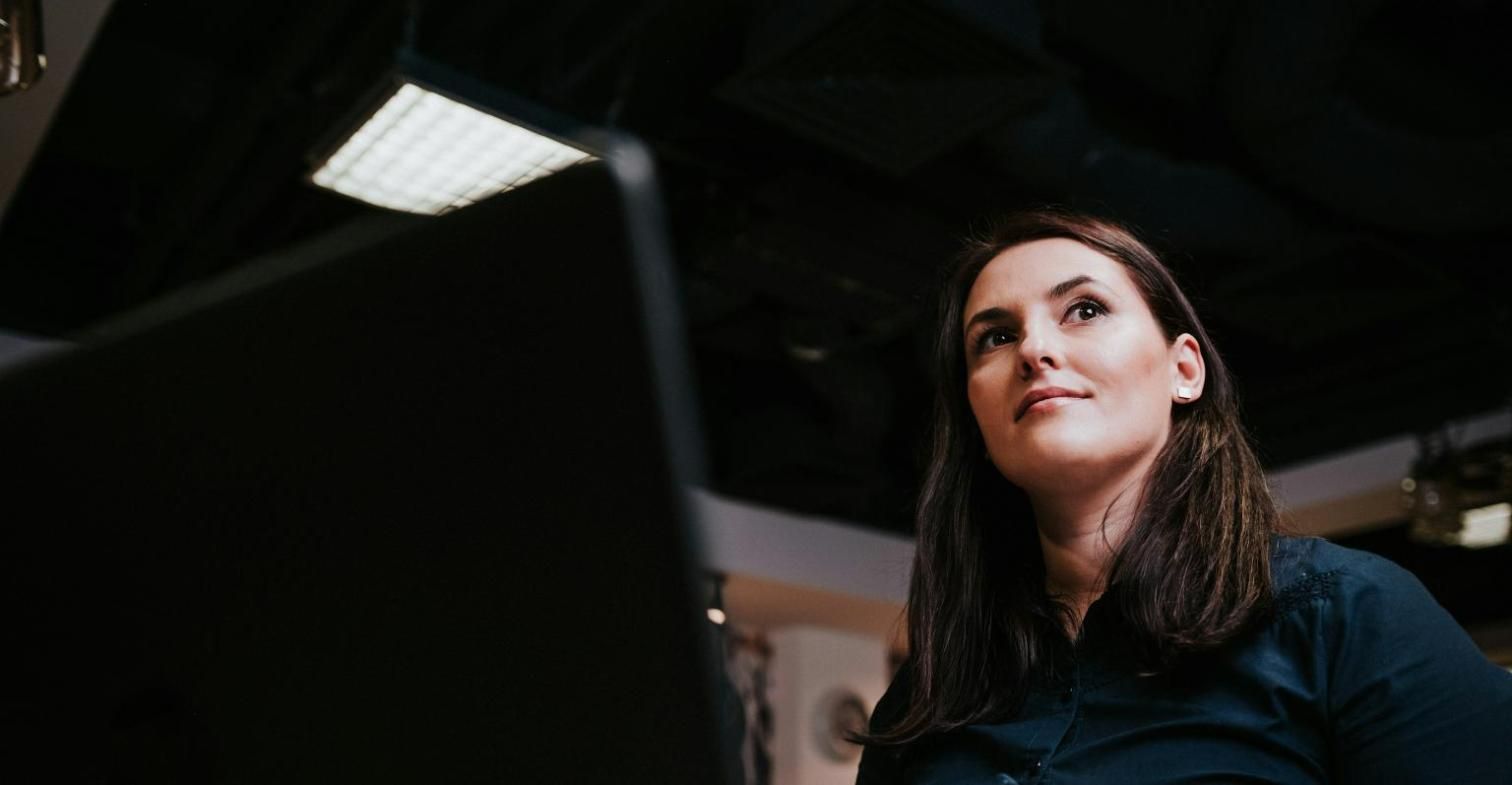 Mujer revisando su pantalla en una oficina con poca luz