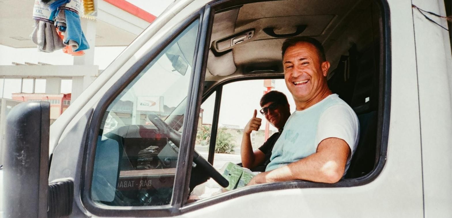 Repartidor sonriendo desde la cabina de su furgoneta