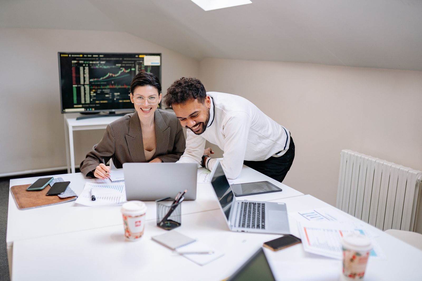 Dos compañeros de un equipo de software sonriendo ante un portátil en una oficina